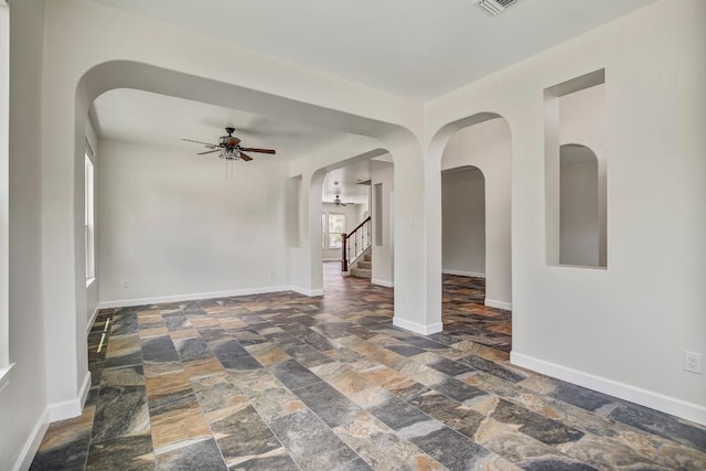 309 Camperdown Elm Dr, Austin, TX 78748 - unfurnished room featuring stone tile floors, ceiling fan, arched walkways, and stairs