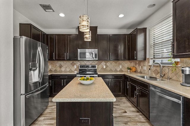 1231 Tumbleweed Trl, Temple, TX 76502 - kitchen featuring appliances with stainless steel finishes, light wood-style flooring, dark brown cabinetry, a kitchen island, and recessed lighting