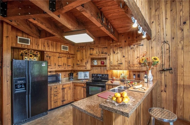 450 Oakwood Loop, San Marcos, TX 78666 - kitchen with black appliances, wooden walls, brown cabinets, a peninsula, and rail lighting