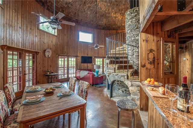 450 Oakwood Loop, San Marcos, TX 78666 - dining space featuring a towering ceiling, concrete floors, a ceiling fan, wood walls, and french doors