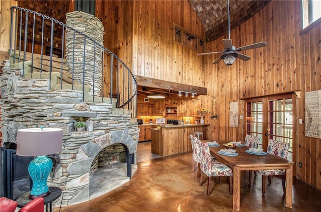 450 Oakwood Loop, San Marcos, TX 78666 - dining area featuring high vaulted ceiling, finished concrete floors, a fireplace, wooden walls, and stairs