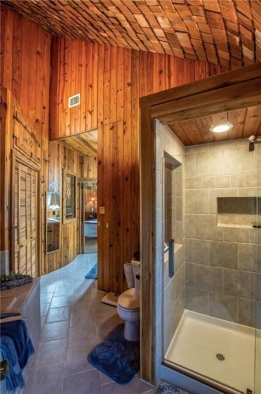 450 Oakwood Loop, San Marcos, TX 78666 - bathroom with lofted ceiling, wooden walls, a stall shower, and tile patterned floors