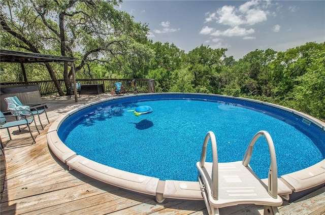 450 Oakwood Loop, San Marcos, TX 78666 - outdoor pool with a wooden deck, a hot tub, and view of scattered trees