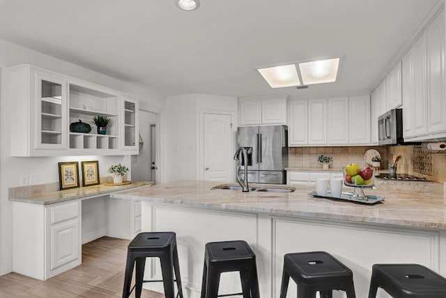13517 Carlos Fifth Ct, Corpus Christi, TX 78418 - kitchen featuring appliances with stainless steel finishes, a peninsula, white cabinets, light stone counters, and glass insert cabinets