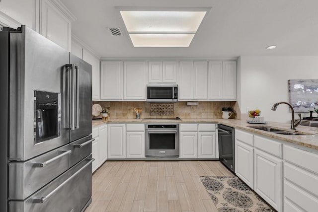 13517 Carlos Fifth Ct, Corpus Christi, TX 78418 - kitchen featuring stainless steel appliances, white cabinets, tasteful backsplash, light stone counters, and light wood finished floors