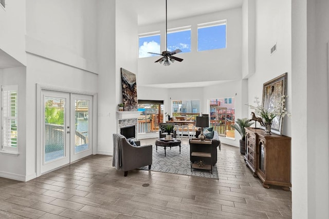 13517 Carlos Fifth Ct, Corpus Christi, TX 78418 - living room featuring wood finished floors, a ceiling fan, a high ceiling, a fireplace, and french doors
