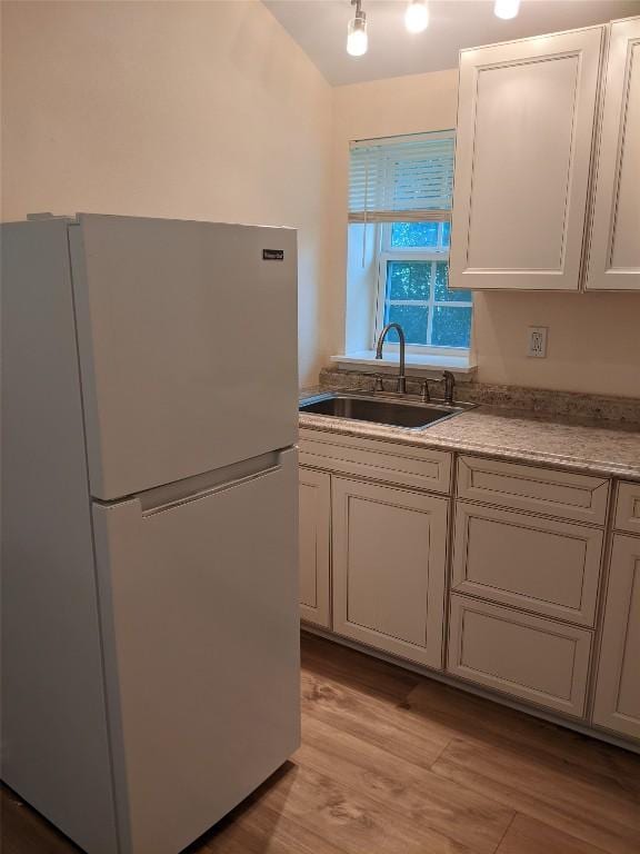 502 Toliver St, Bastrop, TX 78602 - kitchen with freestanding refrigerator, light countertops, light wood finished floors, and white cabinets