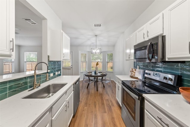 237 Baldwin St, Hutto, TX 78634 - kitchen with appliances with stainless steel finishes, light wood-style floors, tasteful backsplash, and white cabinets