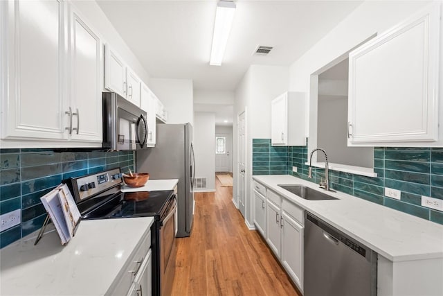 237 Baldwin St, Hutto, TX 78634 - kitchen featuring stainless steel appliances, light wood-style flooring, white cabinetry, and backsplash