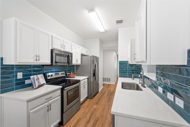 237 Baldwin St, Hutto, TX 78634 - kitchen featuring appliances with stainless steel finishes, decorative backsplash, light wood finished floors, and white cabinetry