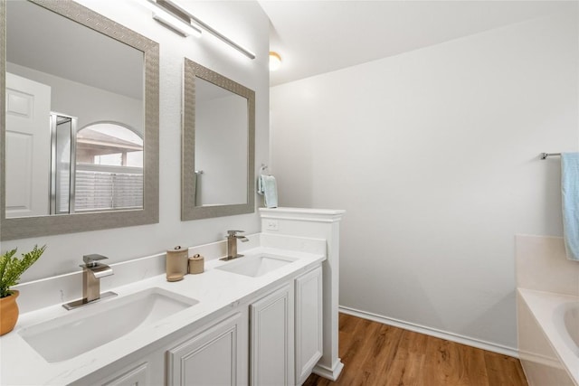 237 Baldwin St, Hutto, TX 78634 - bathroom with double vanity, wood finished floors, and a garden tub