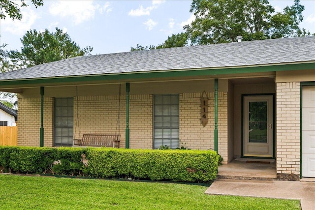 114 Pecan Dr, Elgin, TX 78621 - view of exterior entry featuring brick siding, a shingled roof, and a yard
