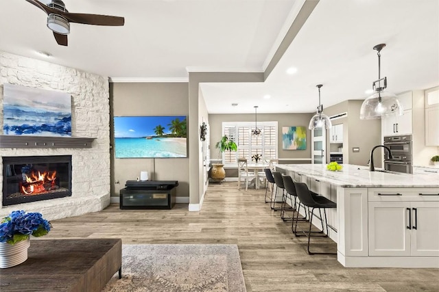 291 Torrington Dr, Austin, TX 78737 - kitchen featuring light stone countertops, white cabinetry, light wood finished floors, ceiling fan, and a kitchen breakfast bar