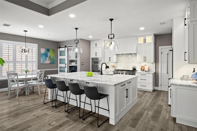 291 Torrington Dr, Austin, TX 78737 - kitchen featuring a barn door, decorative backsplash, recessed lighting, white cabinetry, and premium range hood