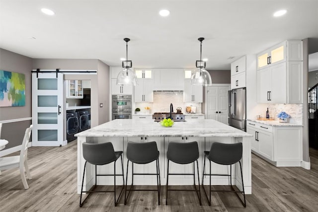 291 Torrington Dr, Austin, TX 78737 - kitchen featuring appliances with stainless steel finishes, separate washer and dryer, tasteful backsplash, a spacious island, and recessed lighting