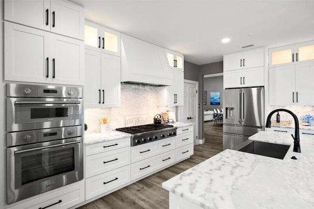 291 Torrington Dr, Austin, TX 78737 - kitchen with appliances with stainless steel finishes, custom exhaust hood, dark wood-style floors, tasteful backsplash, and light stone countertops