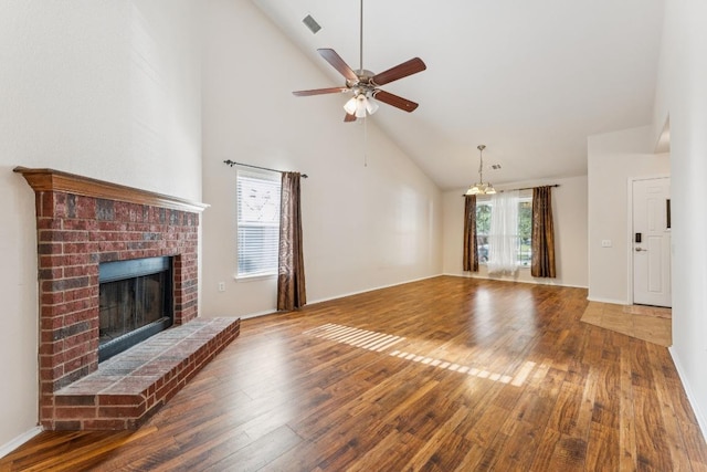 9004 Postvine Dr, Austin, TX 78724 - unfurnished living room featuring high vaulted ceiling, hardwood / wood-style flooring, a brick fireplace, ceiling fan, and a chandelier