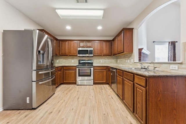 9004 Postvine Dr, Austin, TX 78724 - kitchen featuring stainless steel appliances, light wood finished floors, brown cabinets, decorative backsplash, and recessed lighting