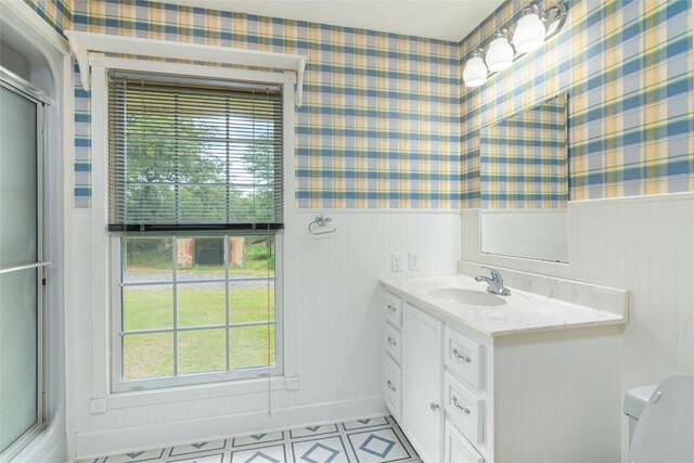 2981 Vivroux Ranch Rd, Seguin, TX 78155 - bathroom featuring vanity, healthy amount of natural light, wallpapered walls, a wainscoted wall, and a shower with shower door