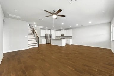 17320 Calipatria Ln, Pflugerville, TX 78660 - unfurnished living room featuring ceiling fan, dark wood finished floors, recessed lighting, and stairway