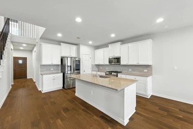 17320 Calipatria Ln, Pflugerville, TX 78660 - kitchen with appliances with stainless steel finishes, tasteful backsplash, dark wood finished floors, recessed lighting, and an island with sink