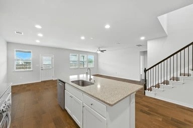 17320 Calipatria Ln, Pflugerville, TX 78660 - kitchen featuring ceiling fan, open floor plan, estacked washer and dryer, dark wood-type flooring, and white cabinetry