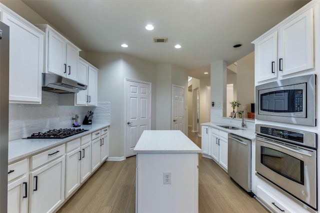 12816 Texas Sage Ct, Austin, TX 78732 - kitchen with stainless steel appliances, under cabinet range hood, a kitchen island, light wood finished floors, and recessed lighting