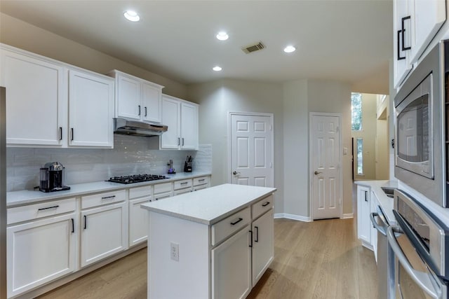 12816 Texas Sage Ct, Austin, TX 78732 - kitchen with appliances with stainless steel finishes, light wood finished floors, backsplash, light countertops, and white cabinets