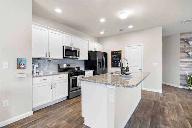118 Craft St, Hutto, TX 78634 - kitchen featuring appliances with stainless steel finishes, a kitchen island with sink, dark wood-type flooring, white cabinetry, and light stone countertops