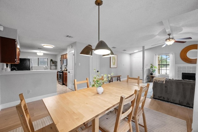 8406 Copano Dr, Austin, TX 78749 - dining space featuring a textured ceiling, light wood-style flooring, a ceiling fan, lofted ceiling, and a fireplace
