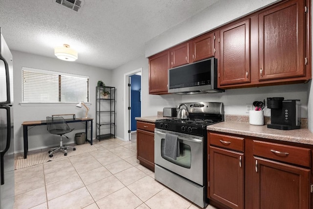 8406 Copano Dr, Austin, TX 78749 - kitchen featuring appliances with stainless steel finishes, light tile patterned flooring, a textured ceiling, light countertops, and a desk