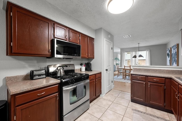 8406 Copano Dr, Austin, TX 78749 - kitchen featuring stainless steel range with gas cooktop, black microwave, a textured ceiling, light tile patterned floors, and light countertops