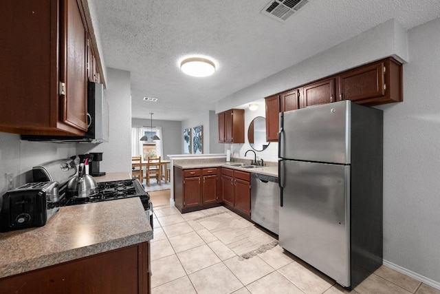 8406 Copano Dr, Austin, TX 78749 - kitchen with appliances with stainless steel finishes, a peninsula, a textured ceiling, and light tile patterned floors