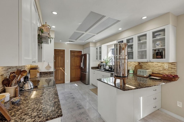 830 Palomino Ln, San Marcos, TX 78666 - kitchen featuring freestanding refrigerator, tasteful backsplash, dark stone countertops, a peninsula, and recessed lighting