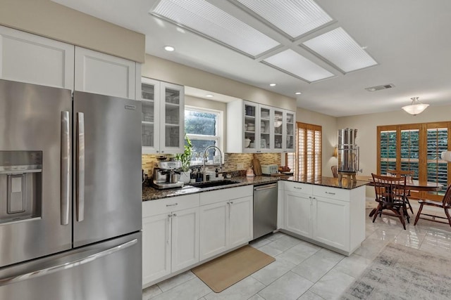 830 Palomino Ln, San Marcos, TX 78666 - kitchen featuring appliances with stainless steel finishes, a peninsula, white cabinetry, dark stone counters, and recessed lighting