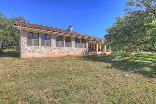 830 Palomino Ln, San Marcos, TX 78666 - rear view of property with a chimney, a tile roof, stone siding, and a lawn