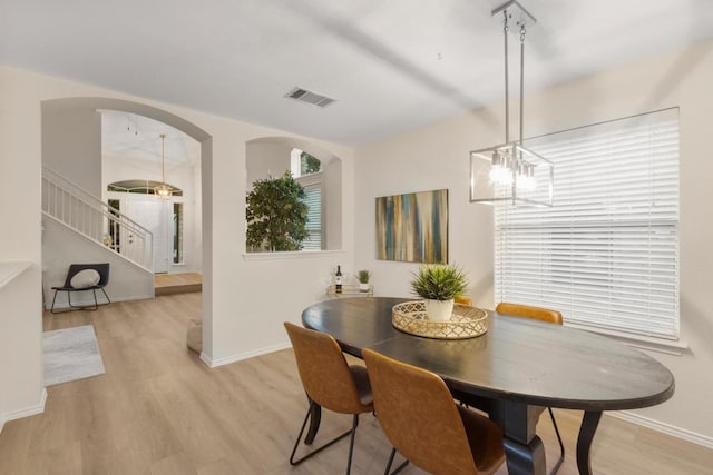 1449 Sir Thopas Trl, Austin, TX 78748 - dining area with light wood finished floors, a chandelier, stairs, and arched walkways