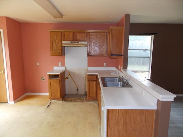 15110 Chamberlain Ct, Austin, TX 78724 - kitchen featuring under cabinet range hood, brown cabinetry, light wood finished floors, and light countertops