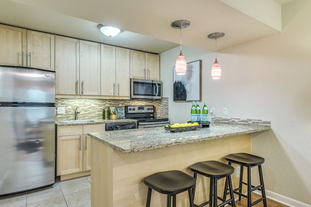 7685 Northcross Dr Unit 907, Austin, TX 78757 - kitchen with appliances with stainless steel finishes, a peninsula, backsplash, a kitchen breakfast bar, and light stone counters