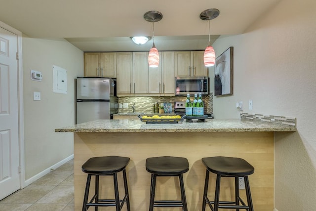 7685 Northcross Dr Unit 907, Austin, TX 78757 - kitchen featuring stainless steel appliances, backsplash, a kitchen bar, a peninsula, and light stone counters