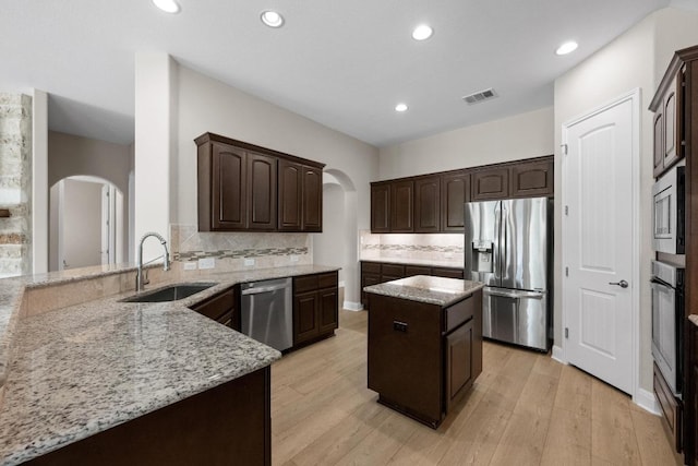 136 Firefall Ln, Austin, TX 78737 - kitchen featuring appliances with stainless steel finishes, arched walkways, a center island, light stone countertops, and recessed lighting