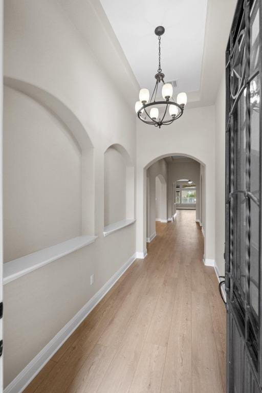 136 Firefall Ln, Austin, TX 78737 - entrance foyer with arched walkways, a chandelier, light wood-style floors, and a raised ceiling