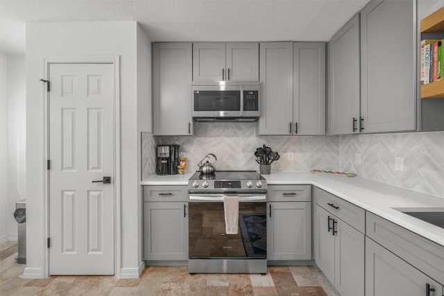 1509 Strickland Dr, Austin, TX 78748 - kitchen with appliances with stainless steel finishes, gray cabinets, tasteful backsplash, and light countertops