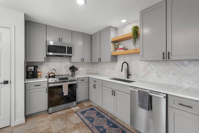 1509 Strickland Dr, Austin, TX 78748 - kitchen with appliances with stainless steel finishes, gray cabinets, backsplash, light countertops, and open shelves