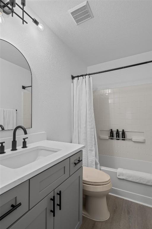 1509 Strickland Dr, Austin, TX 78748 - bathroom with vanity, wood finished floors, shower / bath combination with curtain, and a textured ceiling