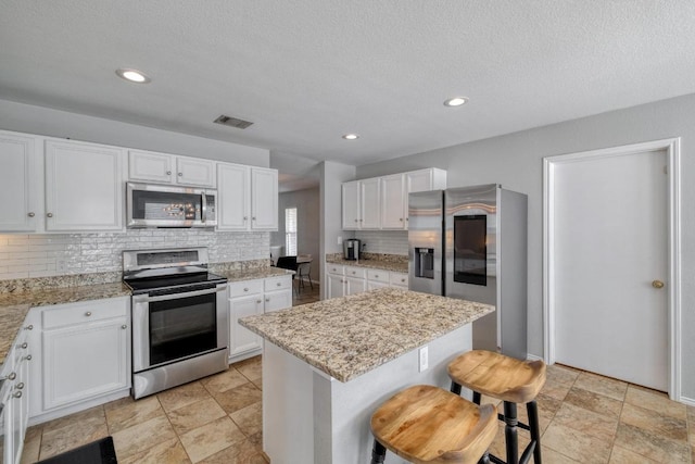 1511 Rhapsody Ridge Dr, Cedar Park, TX 78613 - kitchen with appliances with stainless steel finishes, decorative backsplash, white cabinetry, light stone countertops, and a textured ceiling