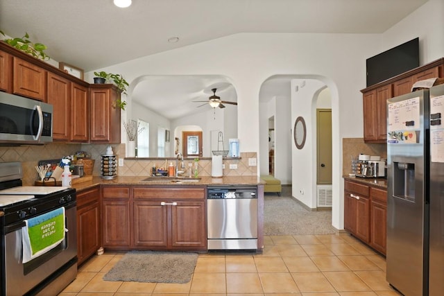 11012 Short Springs Dr, Austin, TX 78754 - kitchen featuring appliances with stainless steel finishes, vaulted ceiling, a ceiling fan, decorative backsplash, and arched walkways