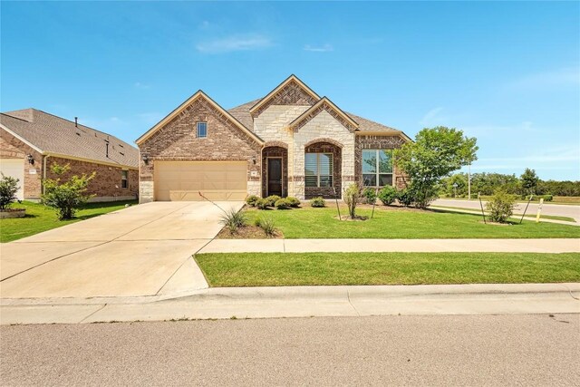 817 Clear Spring Ln, Leander, TX 78641 - french country style house featuring a front yard, driveway, stone siding, a garage, and brick siding