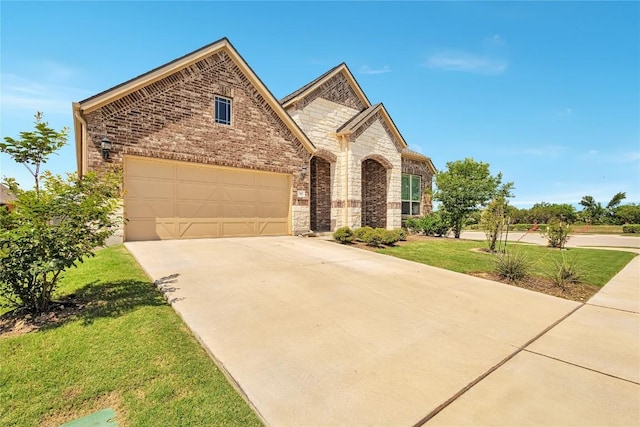 817 Clear Spring Ln, Leander, TX 78641 - french country style house with concrete driveway, stone siding, an attached garage, a front yard, and brick siding