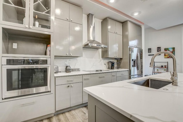 11300 Lake Dr, Austin, TX 78748 - kitchen with appliances with stainless steel finishes, wall chimney range hood, gray cabinets, light wood finished floors, and light stone counters